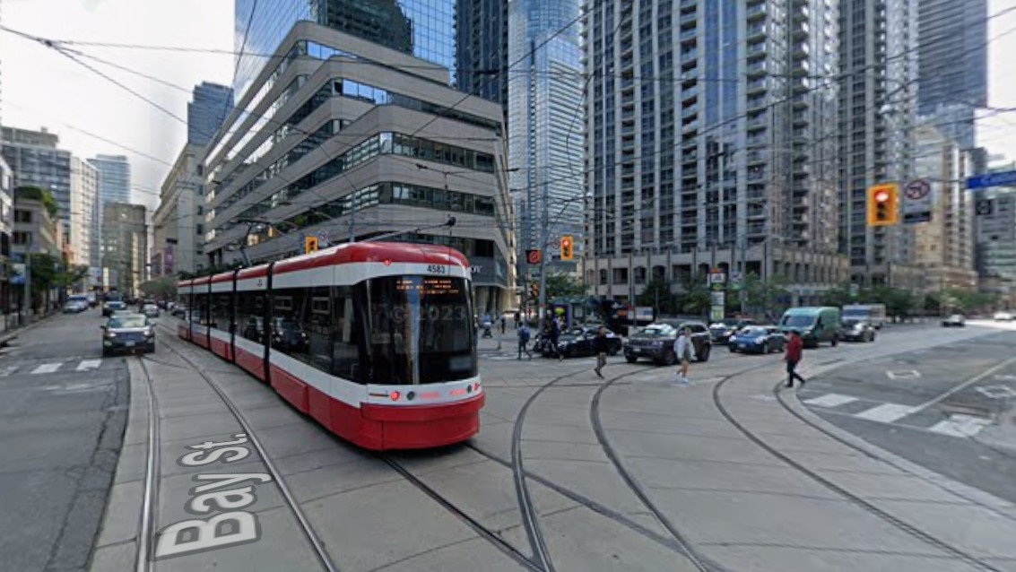 Image of a stretcar running along the busy intersection of College and Bay.