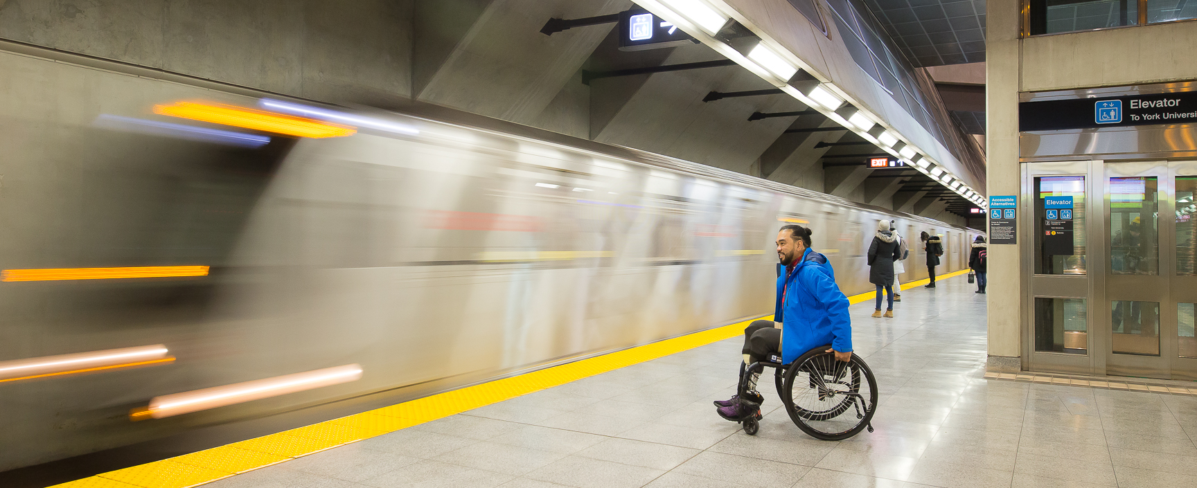 A man with a mobility device waits for the train to stop in the station before he boards.