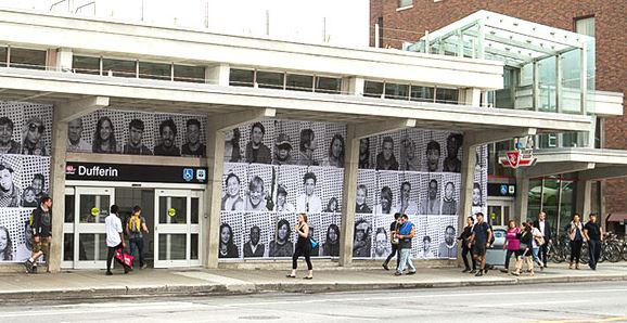 Street view of Dufferin station, with pictures of peoples faces covering the walls of the station.