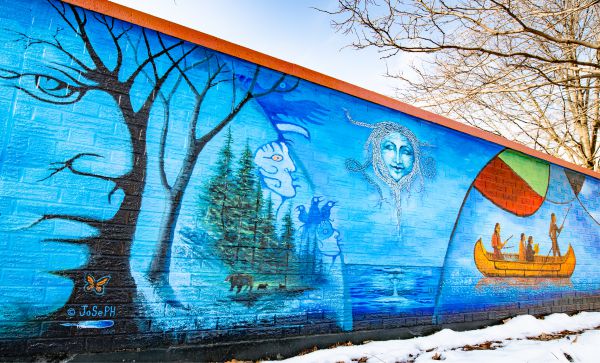 Mural showing native imagery of trees, water and boat