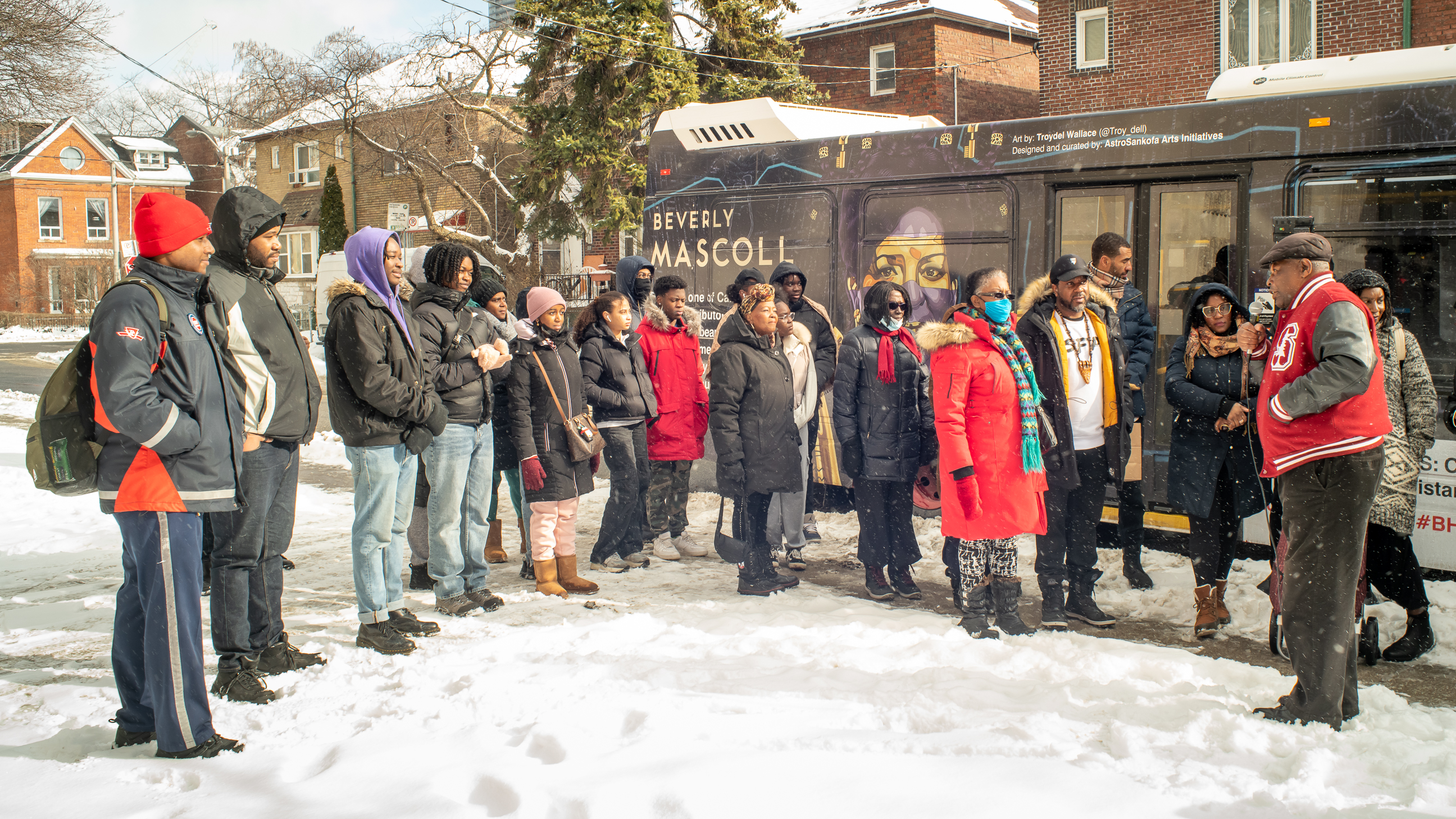 People in semi-circle in front of wrapped bus