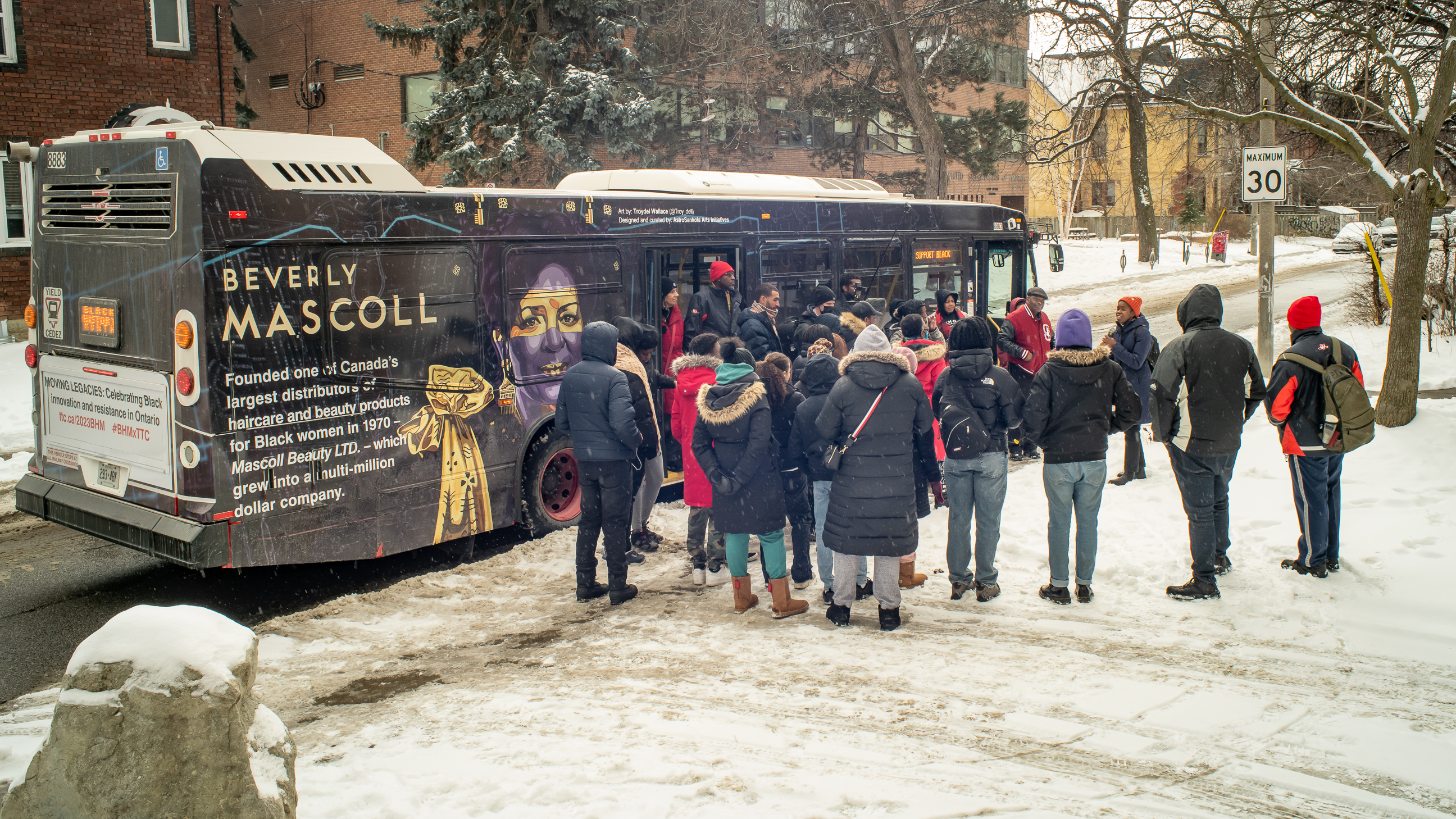 People in semi circle facing a wrapped bus