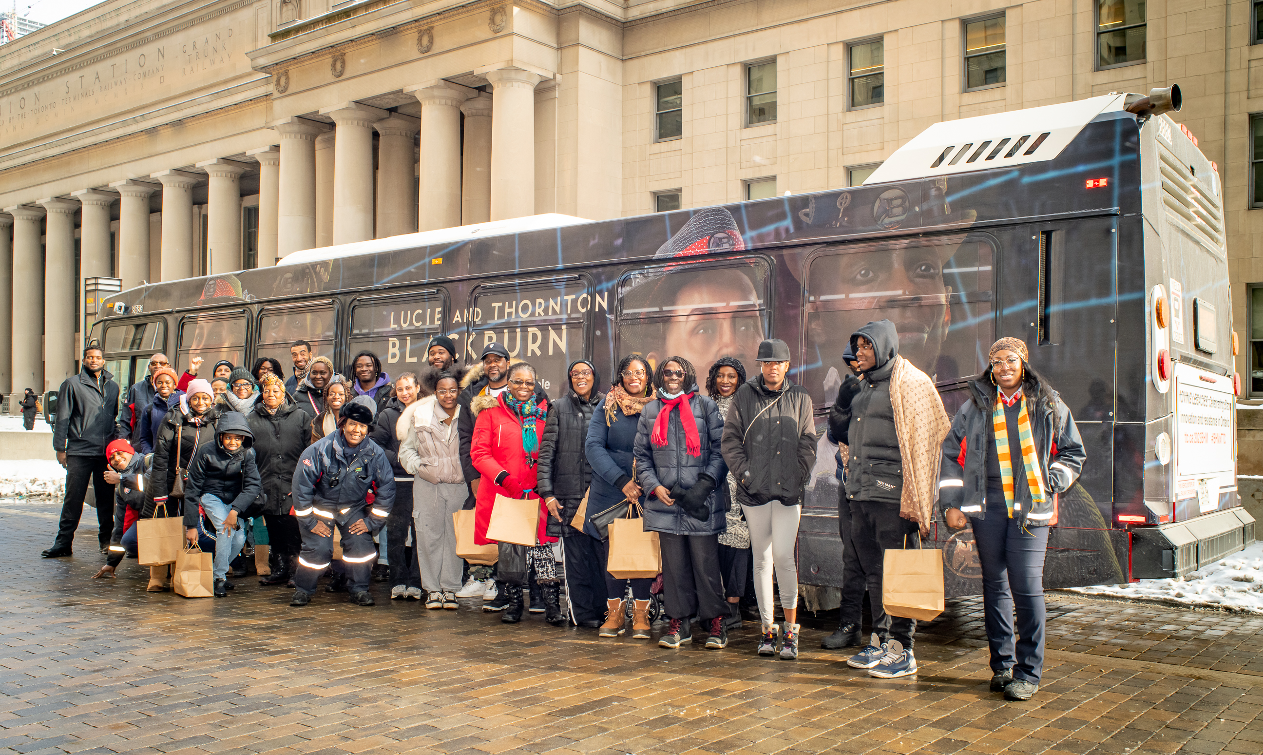 People in line on street in front of wrapped bus