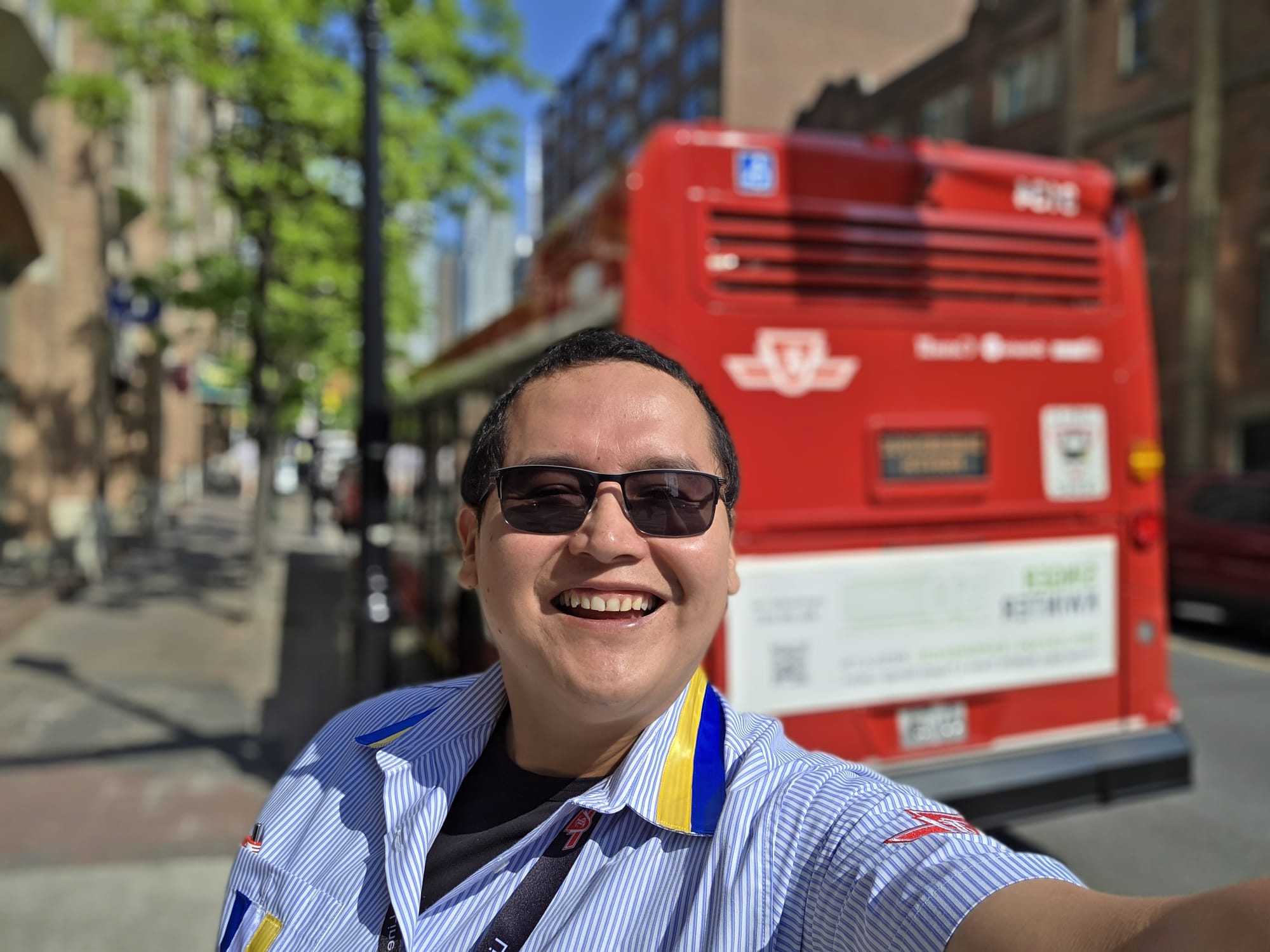 An Indigenous TTC employee posing in front of a TTC bus.