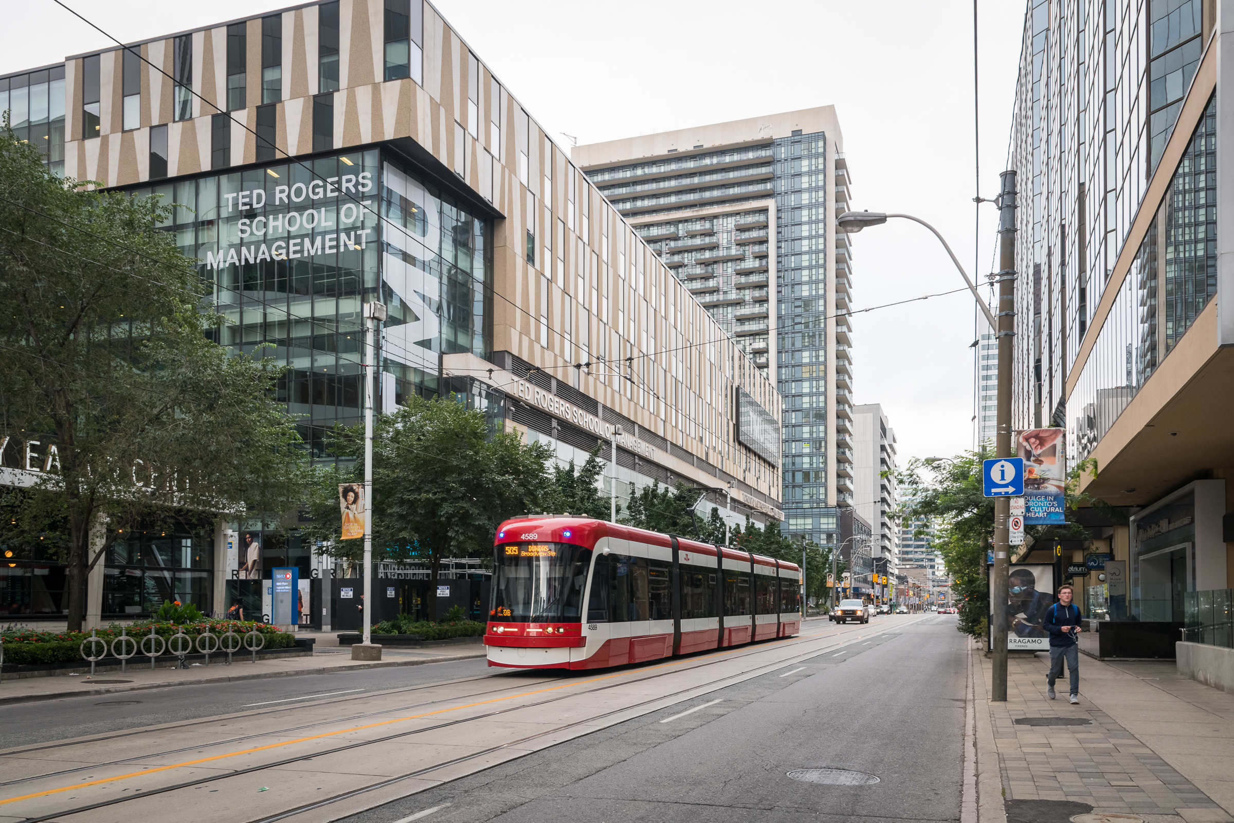 A red and white TTC streetcar going past the Ted Rogers School of Management building.