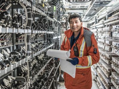 Engineer reviewing plans in front of a bank of electronics