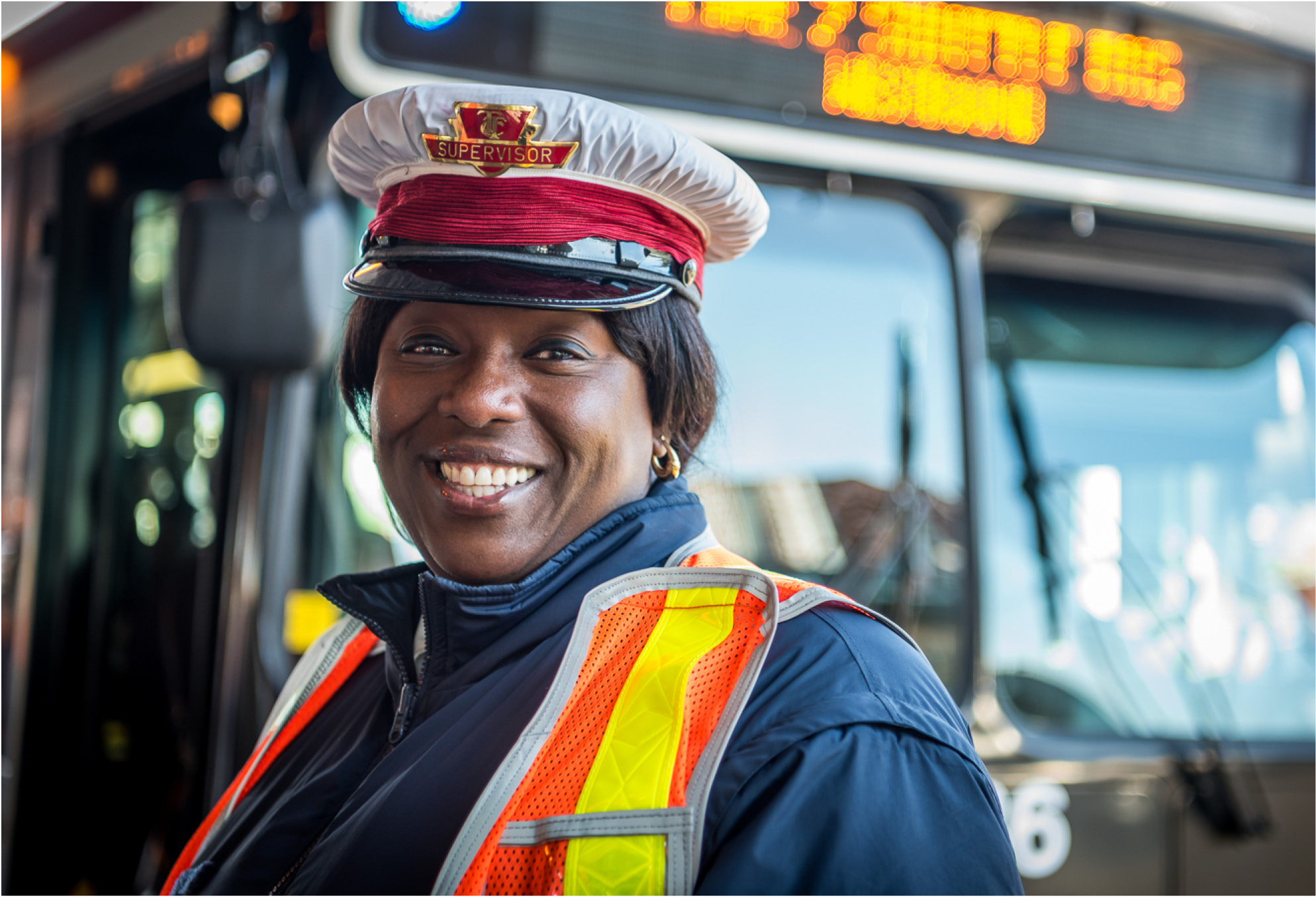 smiling TTC woman bus operator in uniform and orange safety vest on