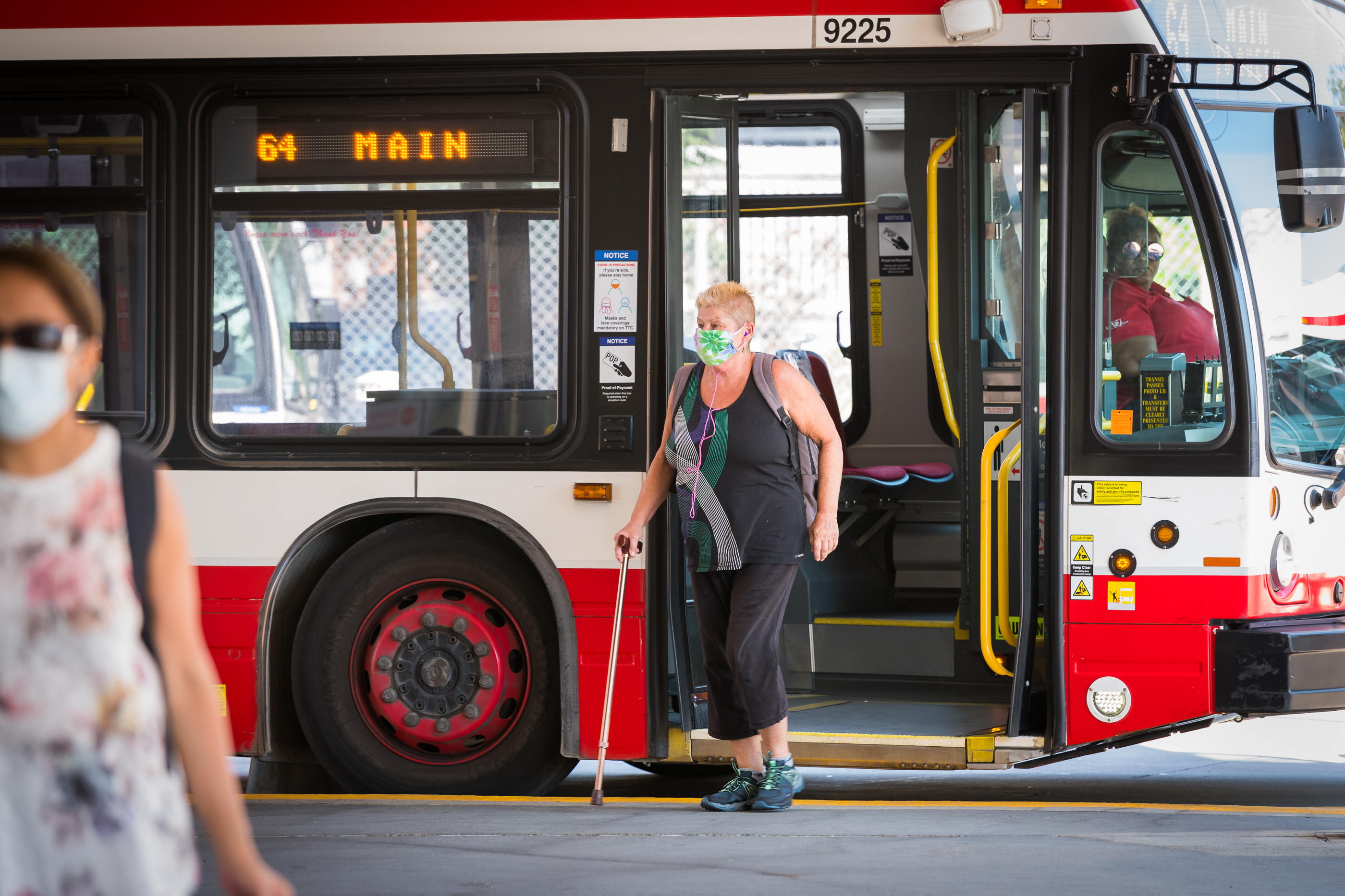 Customer wearing a face mask deboards a 64 Main route bus at a terminal station.