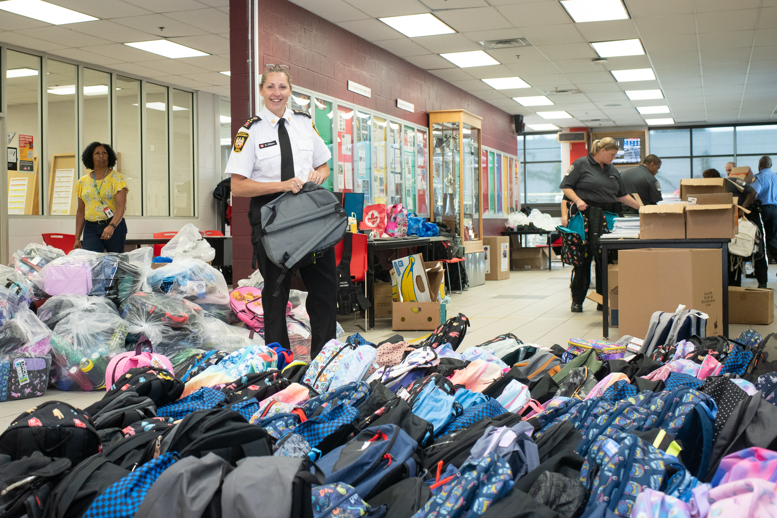 A TTC Enforcement Officer smiles as she is surrounded by filled backpacks for the drive.