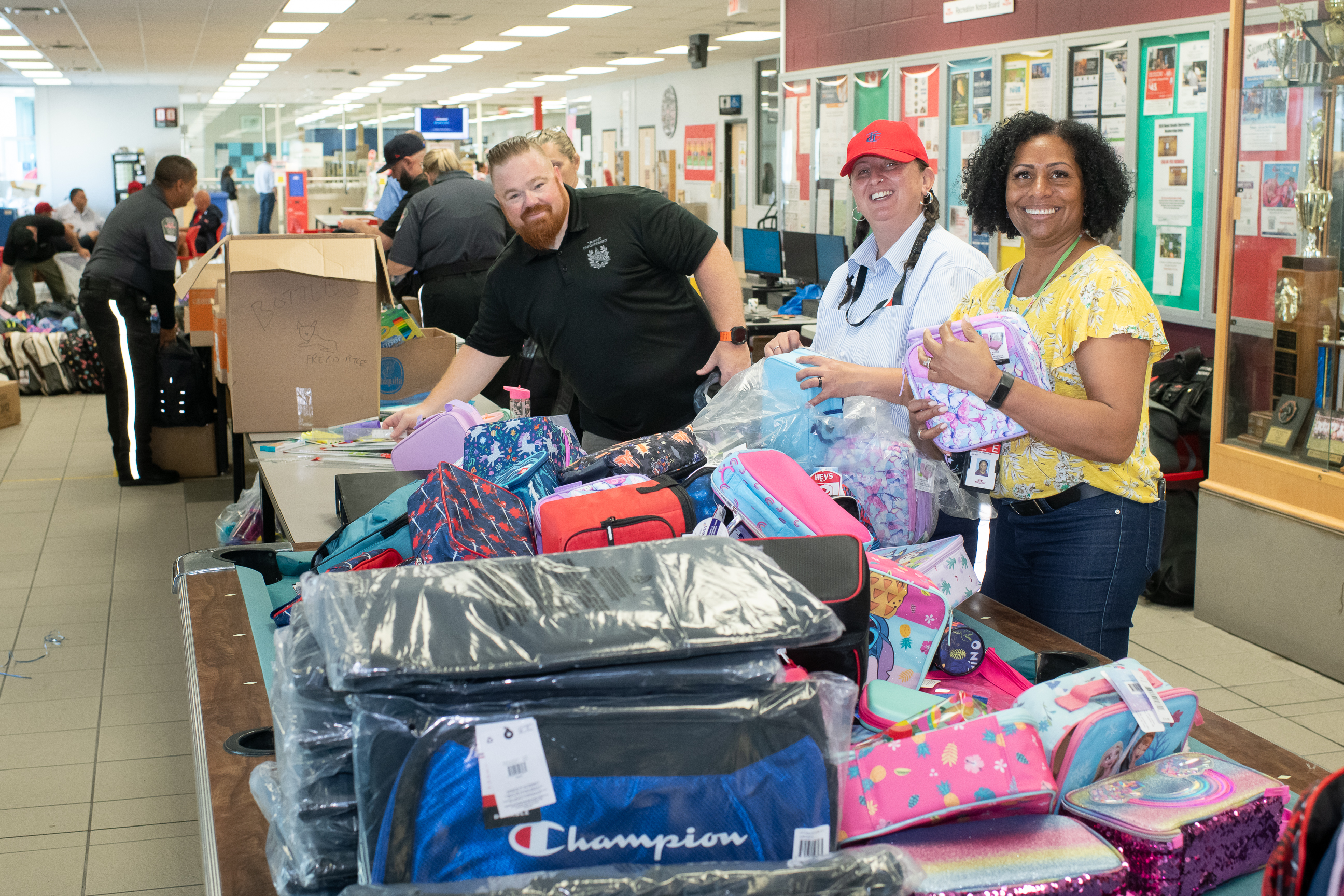 Group of TTC staff smile as they prepare backpacks to be filled.