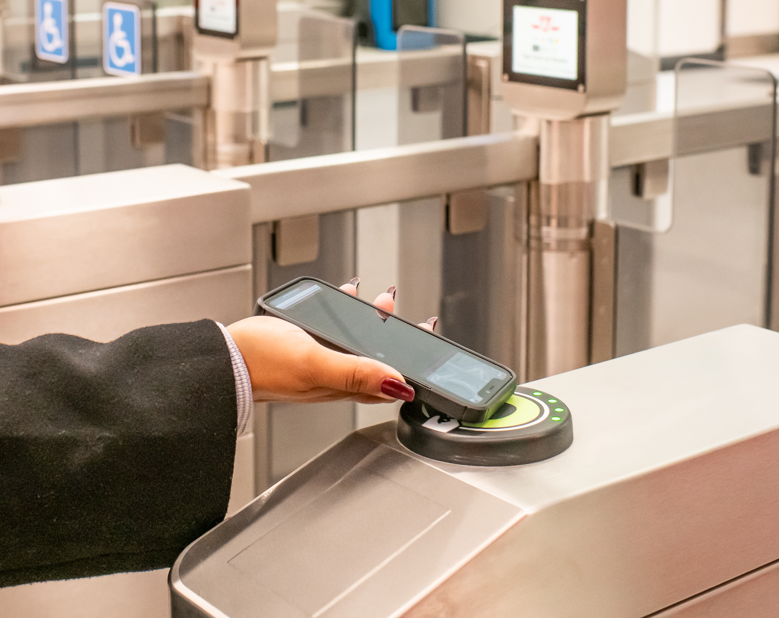 A person's hand tapping a mobile device on a PRESTO fare reader at a TTC station fare gate