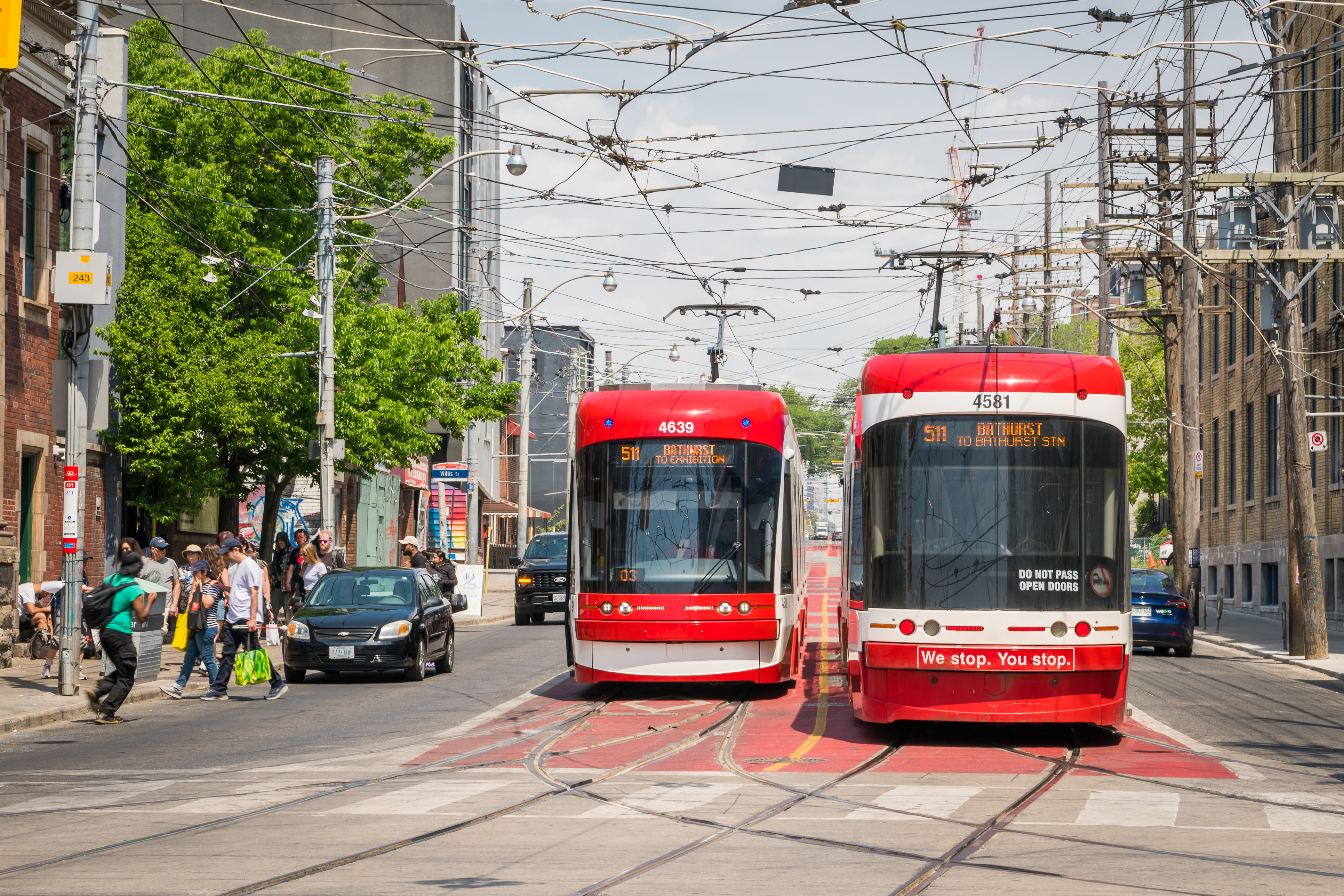 Two 511 Bathurst streetcars passing on a street.