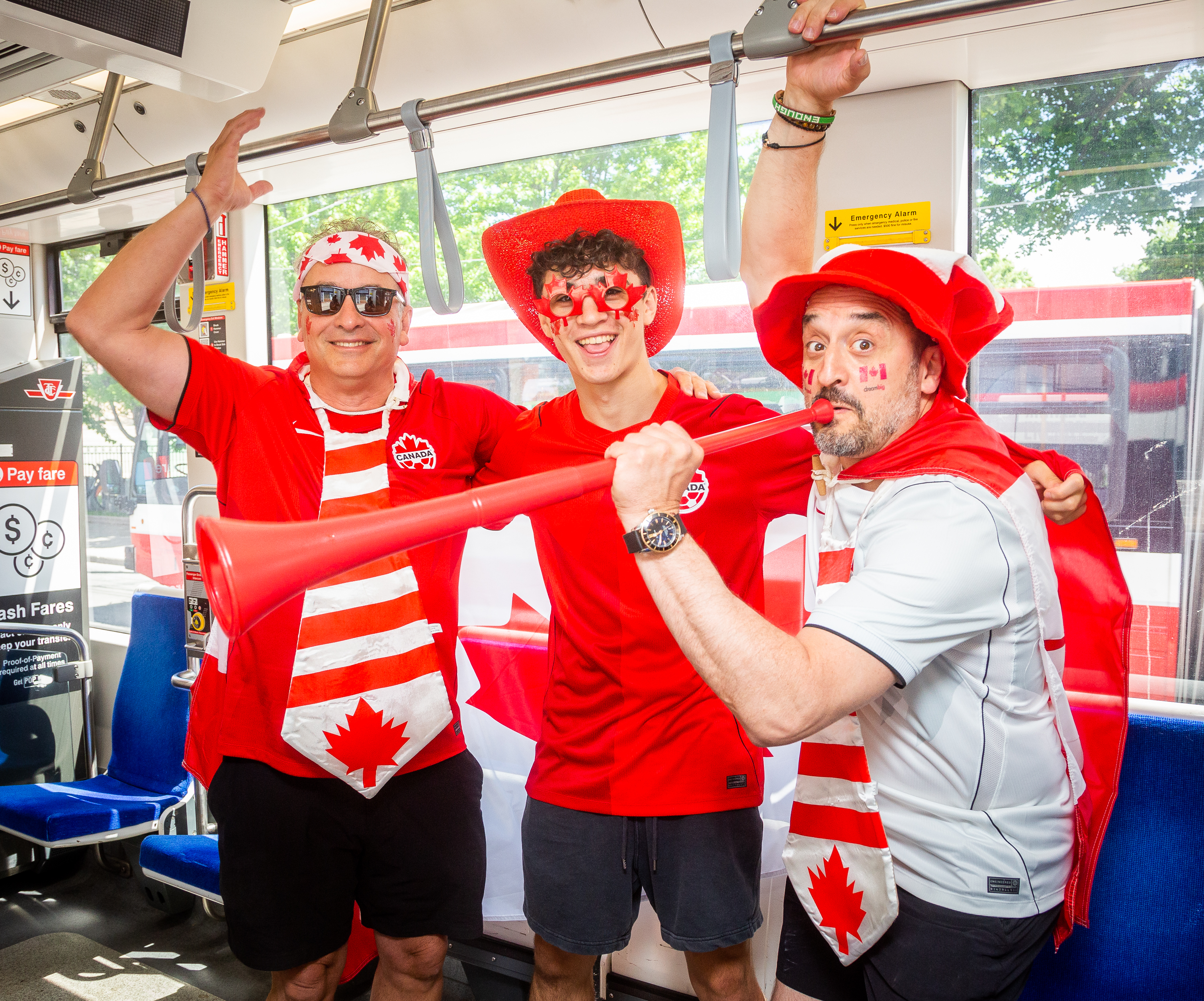 A group of Team Canada fans with Canadian themed outfits on a TTC bus. 