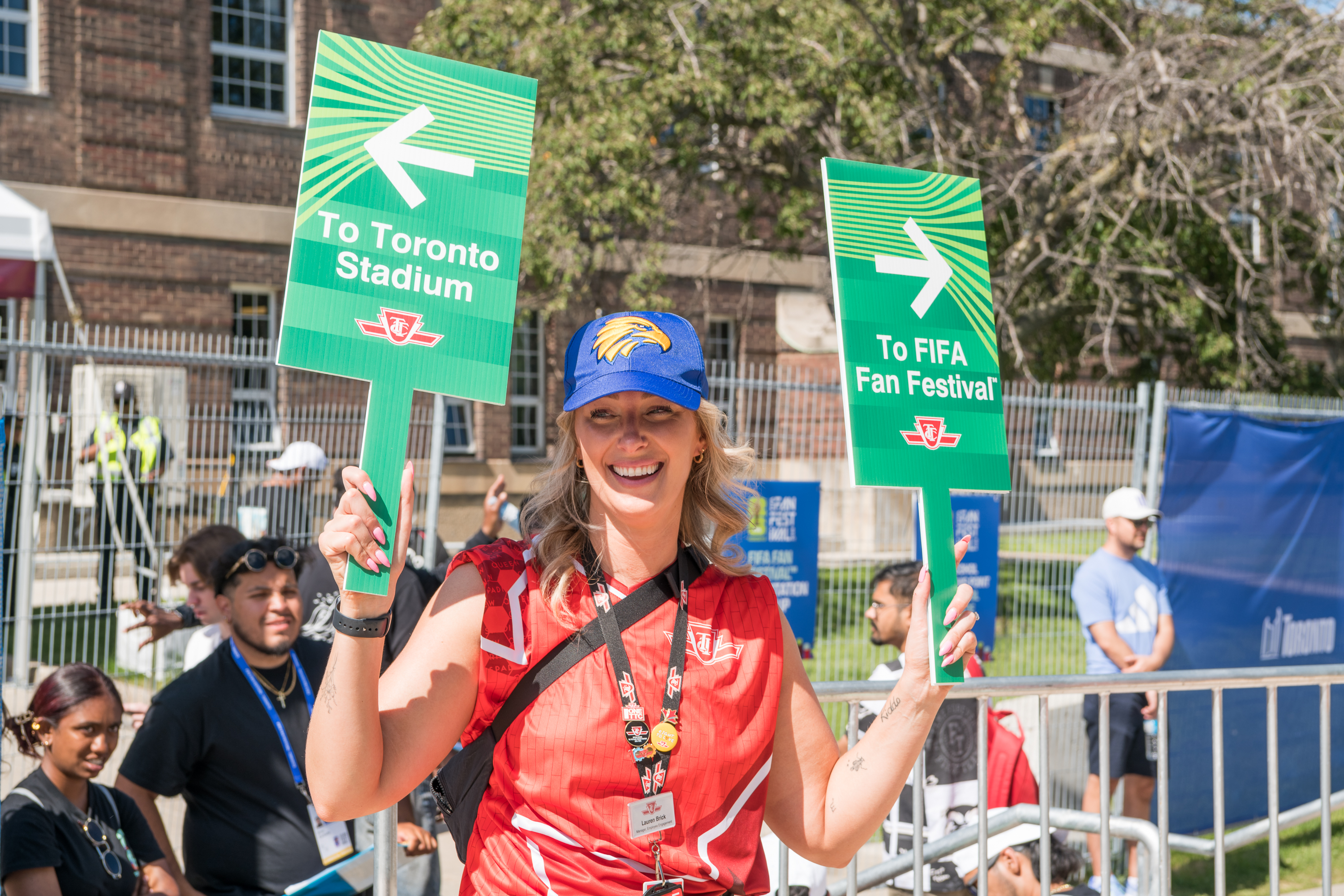 A TTC employee holding two signs, directing fans to Toronto Stadium and FIFA Fan Festival 
