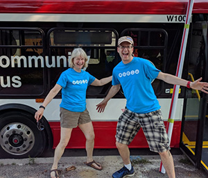 Smiling Yuval Grinspun and Kathleen Barret posing in front of the Community Bus
